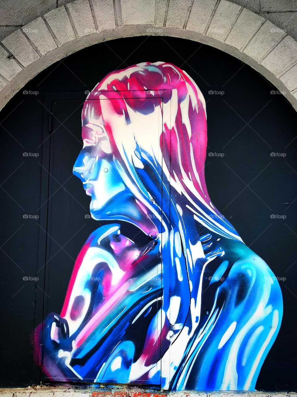 Street art. Graffiti. There is a woman on the wall. Multi-colored colors of paints perfectly contrast with each other. Unusual color find