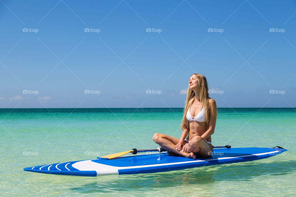 Blonde woman sitting on the sup board 