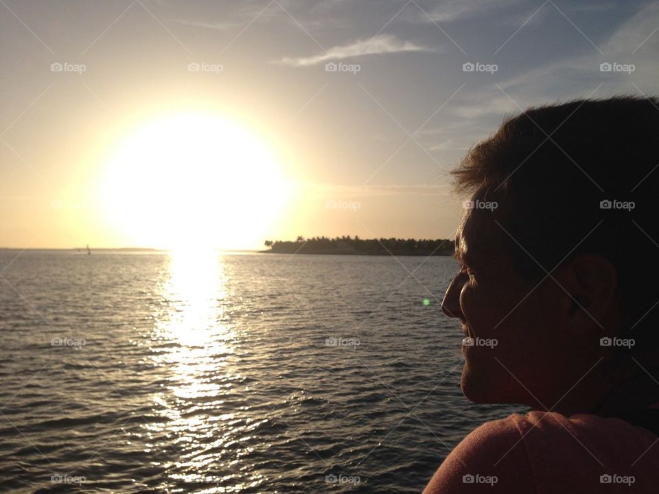 Man looks the sea at sunset 