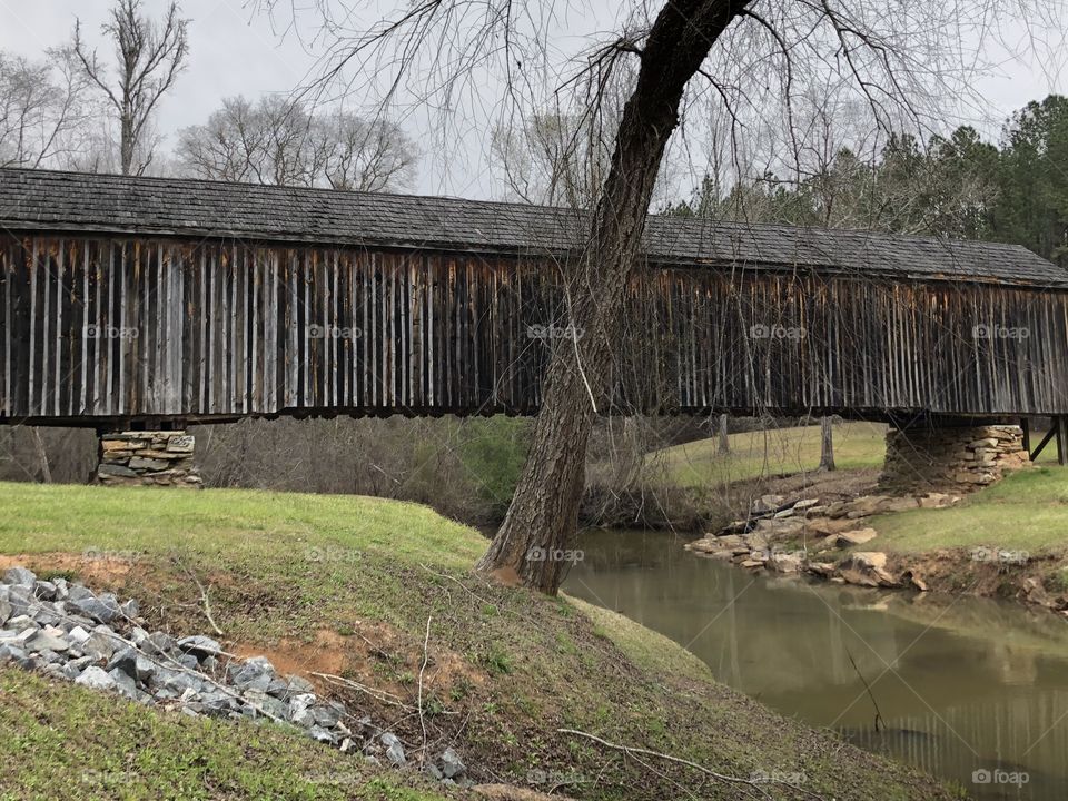 A 120 foot long wooden covered bridge over water. 
