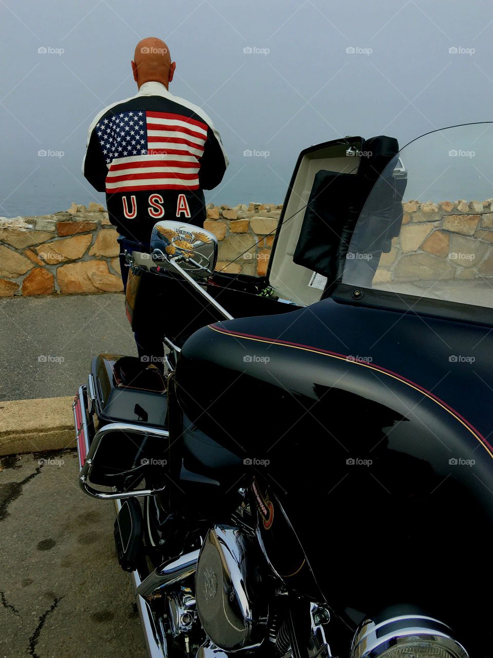 Fog dense on urban bike ride to beach area on Harley Davidson. Driver standing on sidewalk.