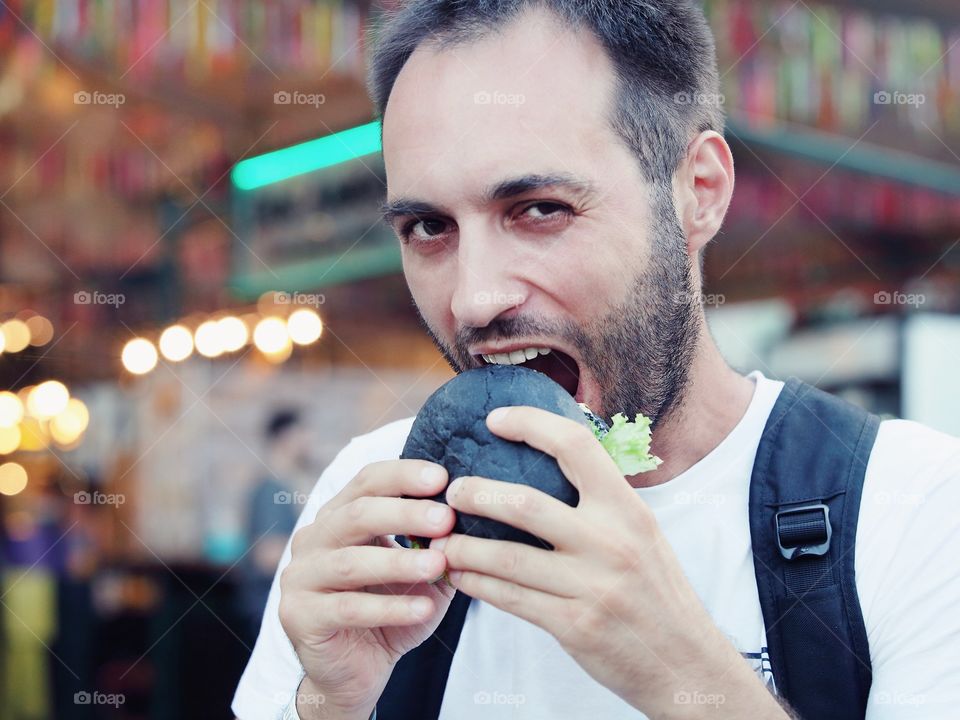 Man eating a black burger