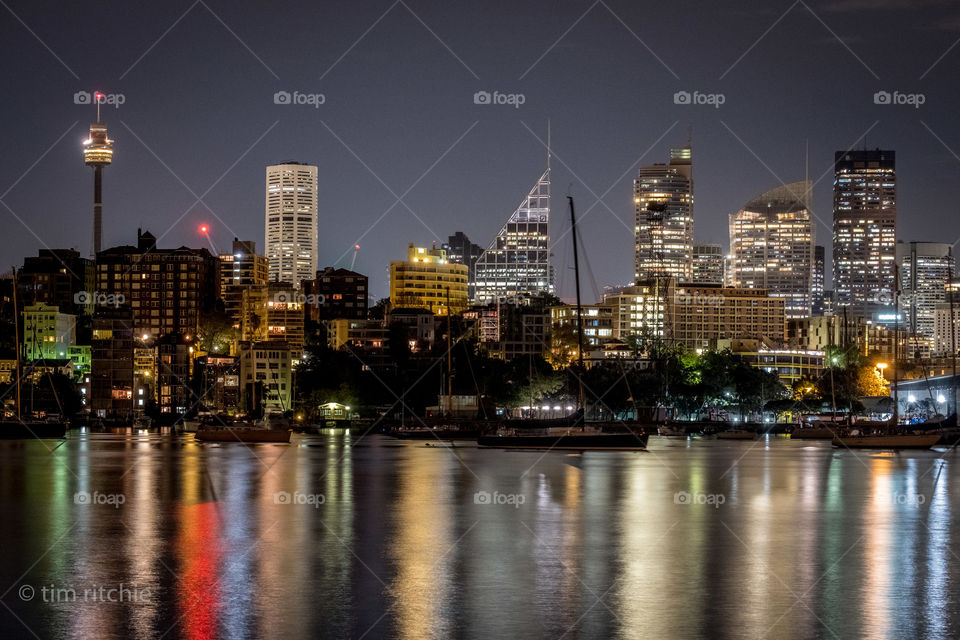 City lights reflecting on Rushcutters Bay in the foreground, with mid 20th C apartments at Elizabeth Bay in the midground and mid town Sydney in the background