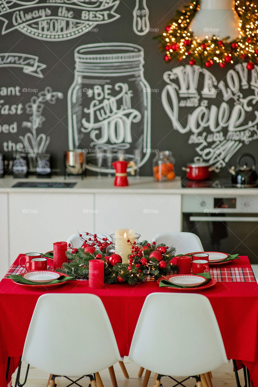 Festive winter cozy kitchen interior with garlands, decorations and gifts.  Christmas dinner at the decorated table.