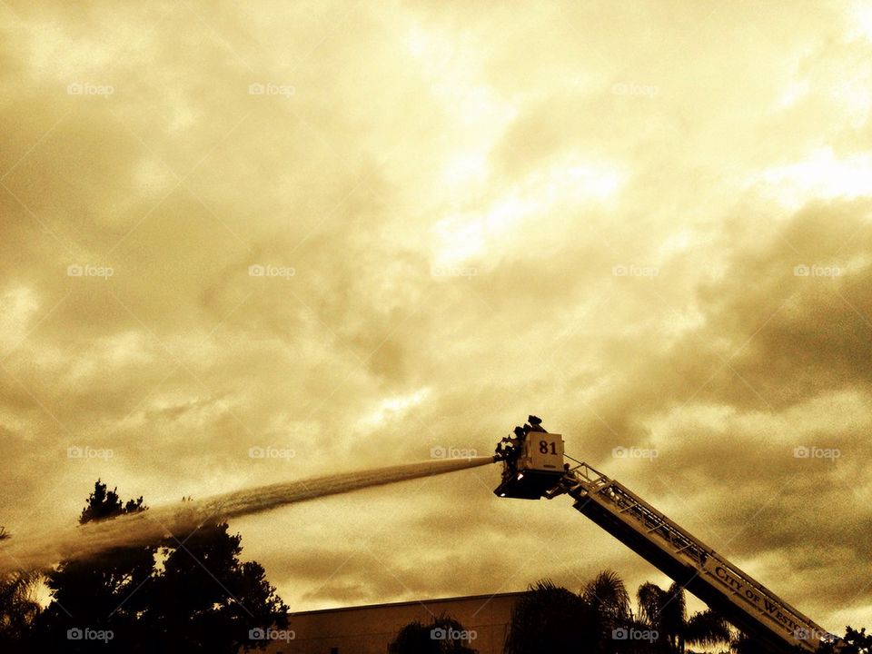 Firemen on a ladder using hose