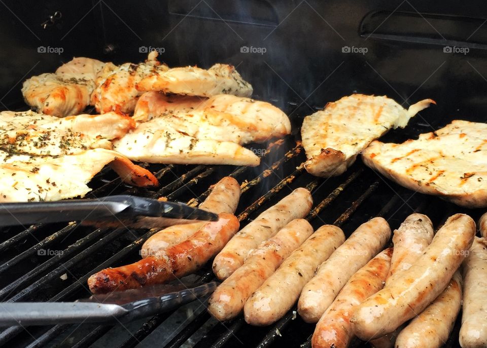 Barbecue time. Chicken and sausages cooking on the barbecue 