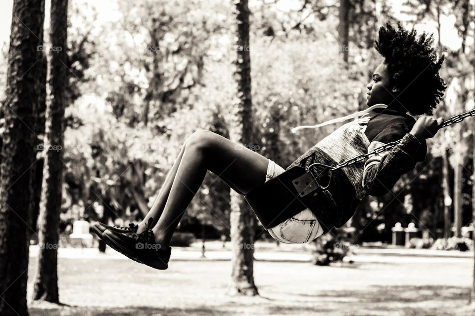 A girl swinging in a park in the woods. Capturing a moment that is simple enough, speaks volumes when you reminisce on how easy and simple life is as a child.