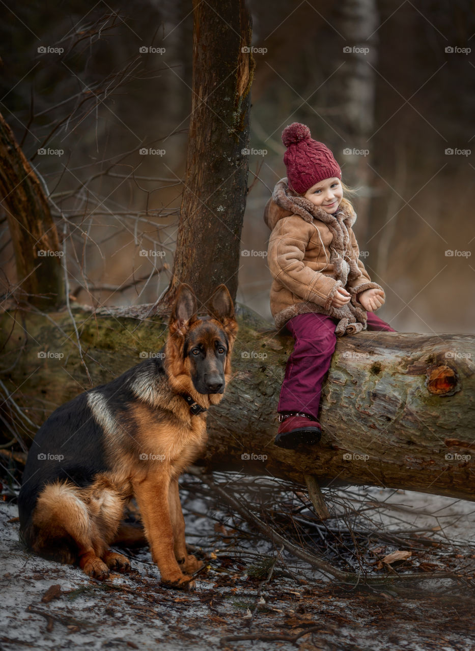 Little girl with German shepherd 6-th months puppy at early spring forest