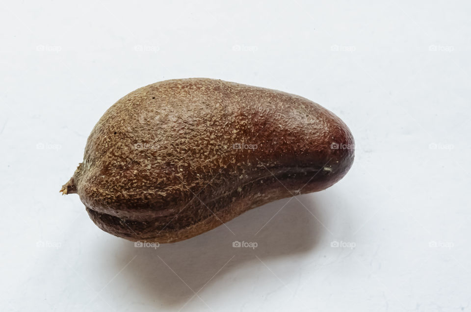 A Small Whole Locust Fruit On A White Background