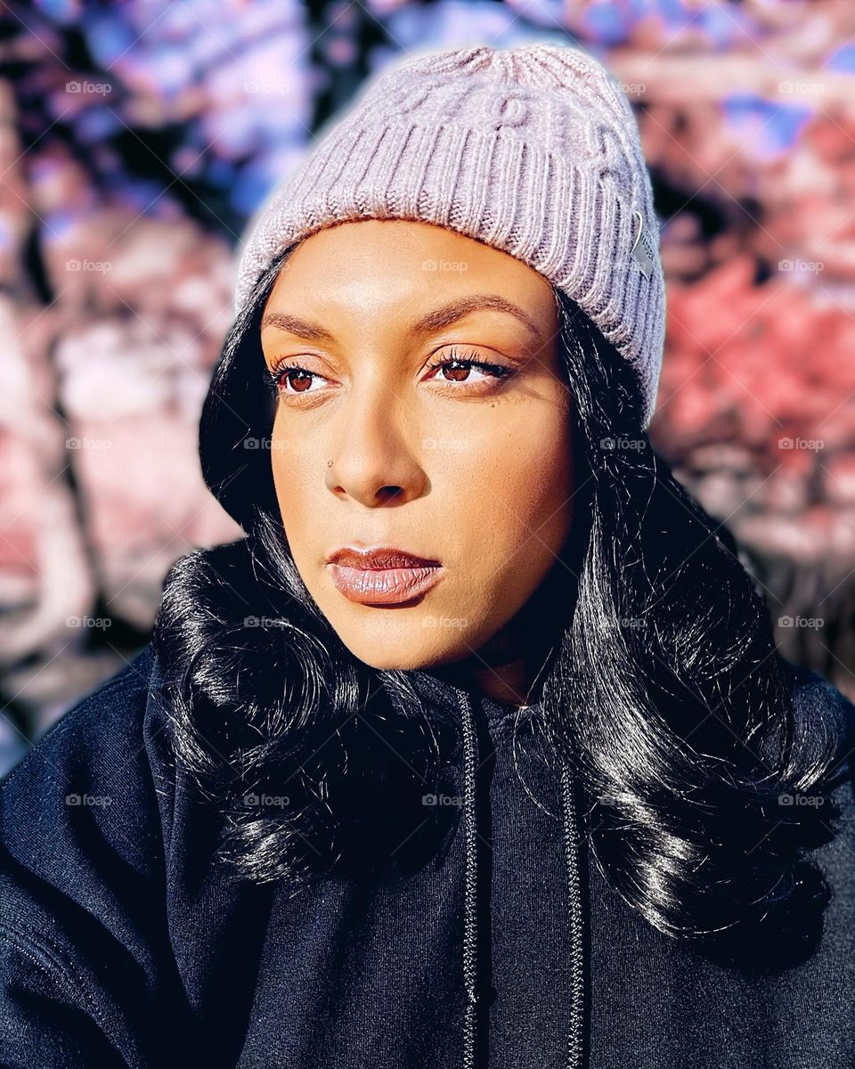 A woman with a light purple beanie and a black hoodie.