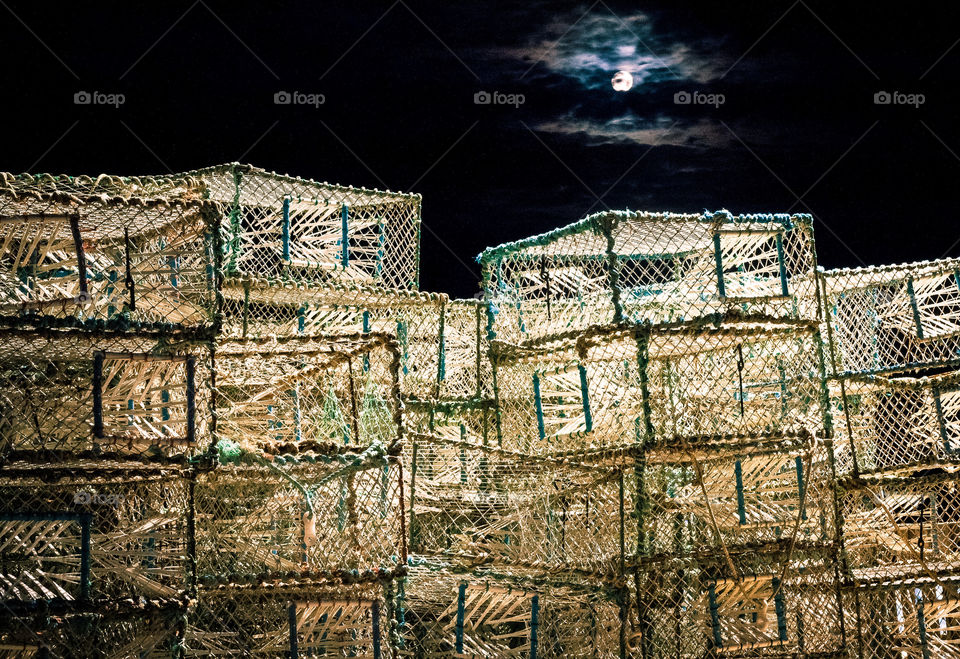 The moon briefly appears appears from behind the clouds to help illuminate a large stack on lobster and crab pots