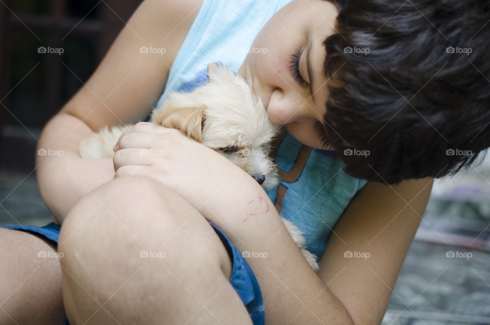 Child kissing a puppy 