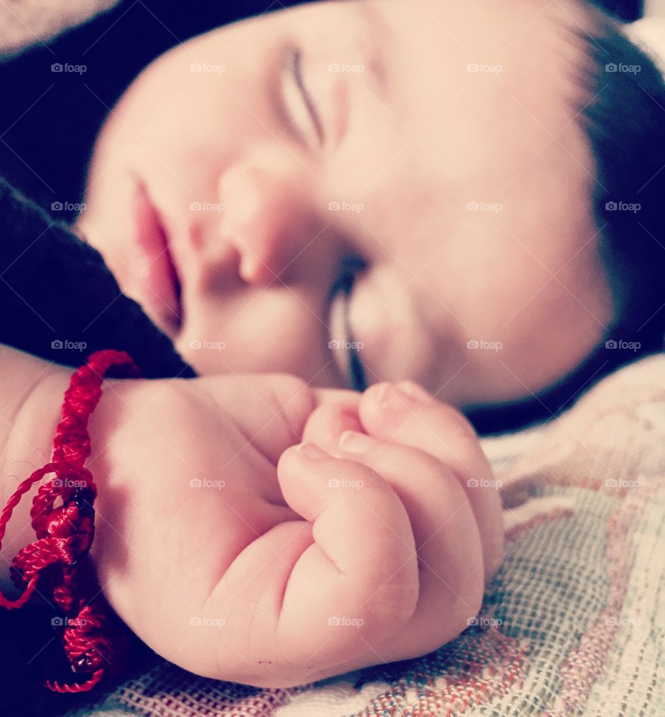 Close-up of cute kid hand and face while sleeping on bed