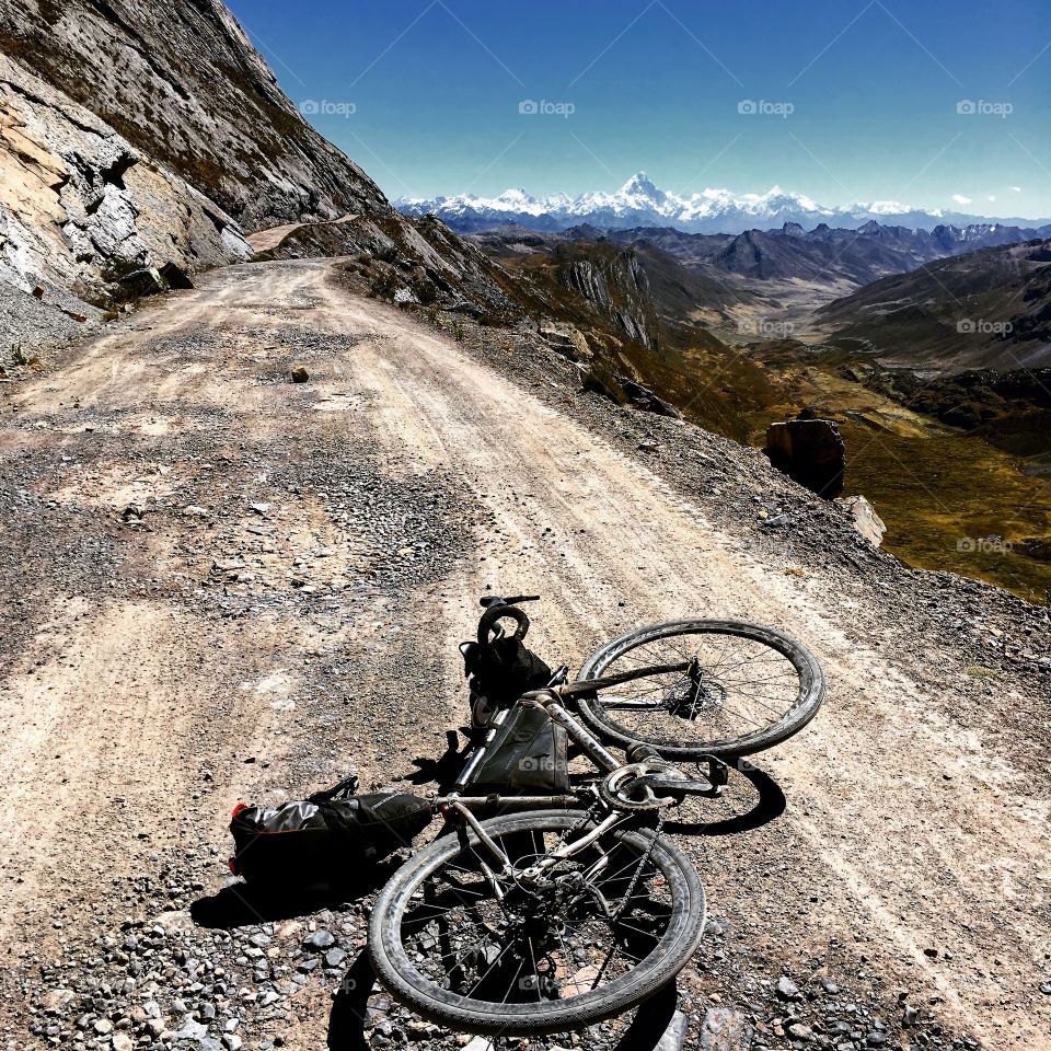 Cycling on big gravel roads up in the Andes mountains South America Peru. Riding a titanium gravel bike loaded with bikepacking gear! Snow capped mountains in the background Bicycle touring to an extreme! 