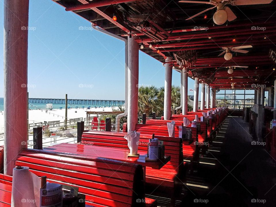 red tables and bench seats at Pensacola Beach front restaurant, perspective and architecture.