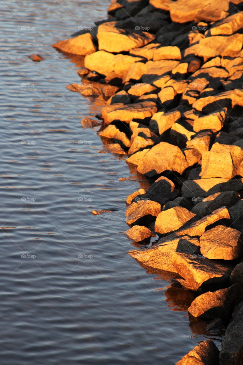 morning light shining on the rocks on shore.