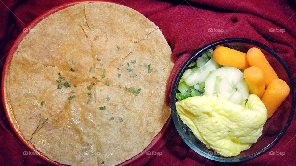 Wheat quesadilla with pepper jack cheese and jalapeños and a glass bowl with cucumbers, broccoli, cauliflower, baby carrots, and scrambled eggs.