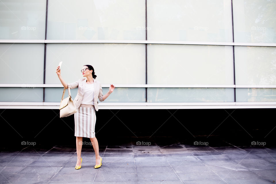 Fashionable woman taking selfie with smartphone