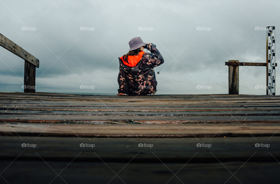 girl watching with binoculars on the pier