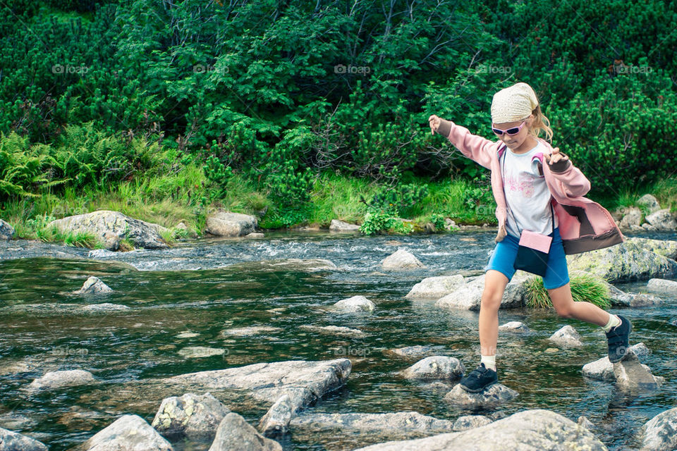 Little girl jumping from stone to stone