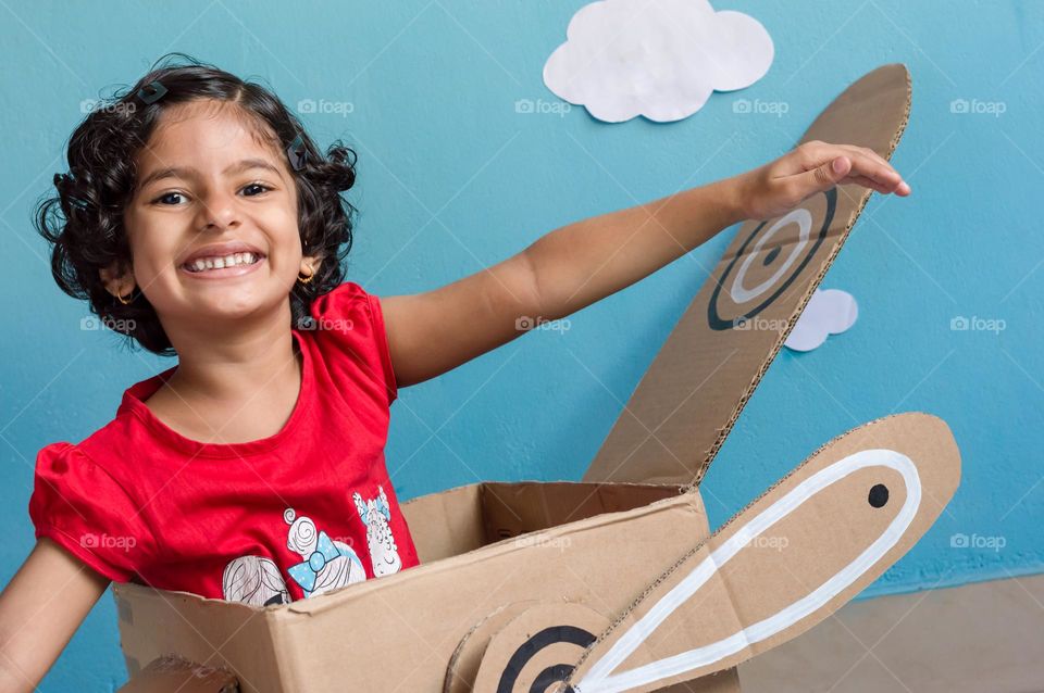 Kid enjoying diy carton box aeroplane.