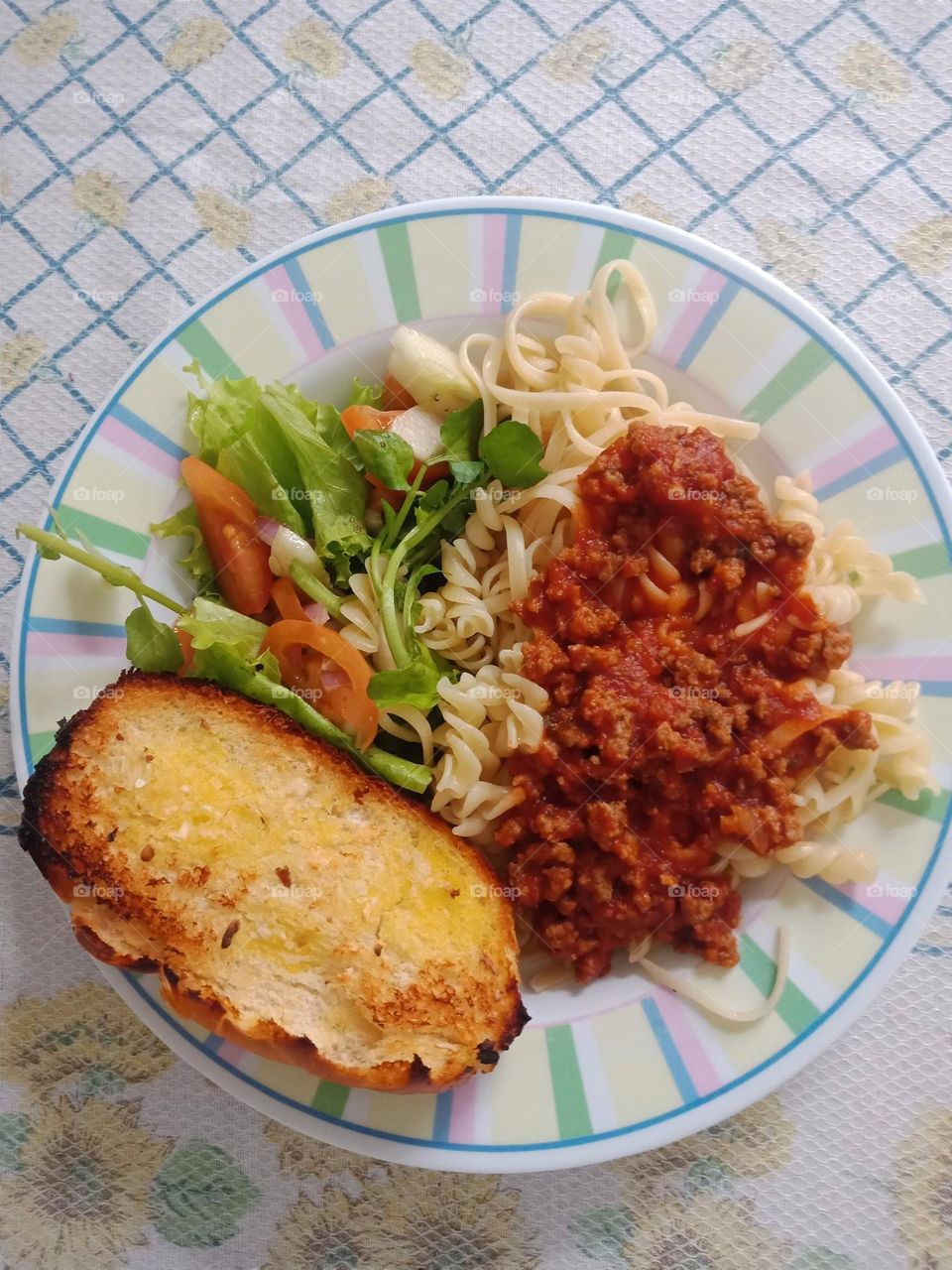 Eating pasta, salad and garlic bread at home