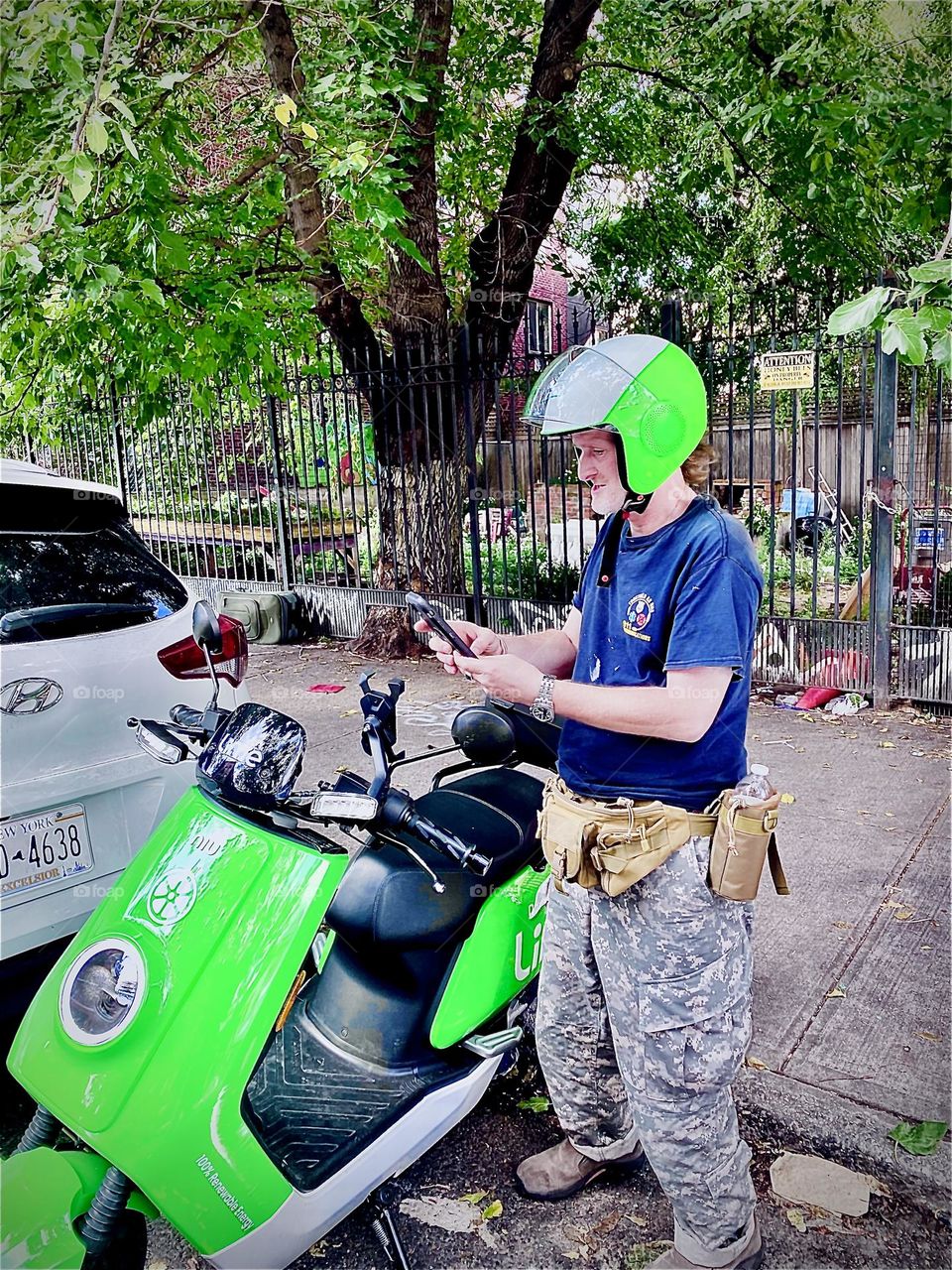 Electro scooter rider Tim Trespas just got off his vehicle to run errands in Bushwick, Bklyn near the “Myrtle Ave & B‘way” M train station. The intense day-glow color of the LIME mopeds & helmets makes sure you are seen. 2021. Hypnotic Productions 