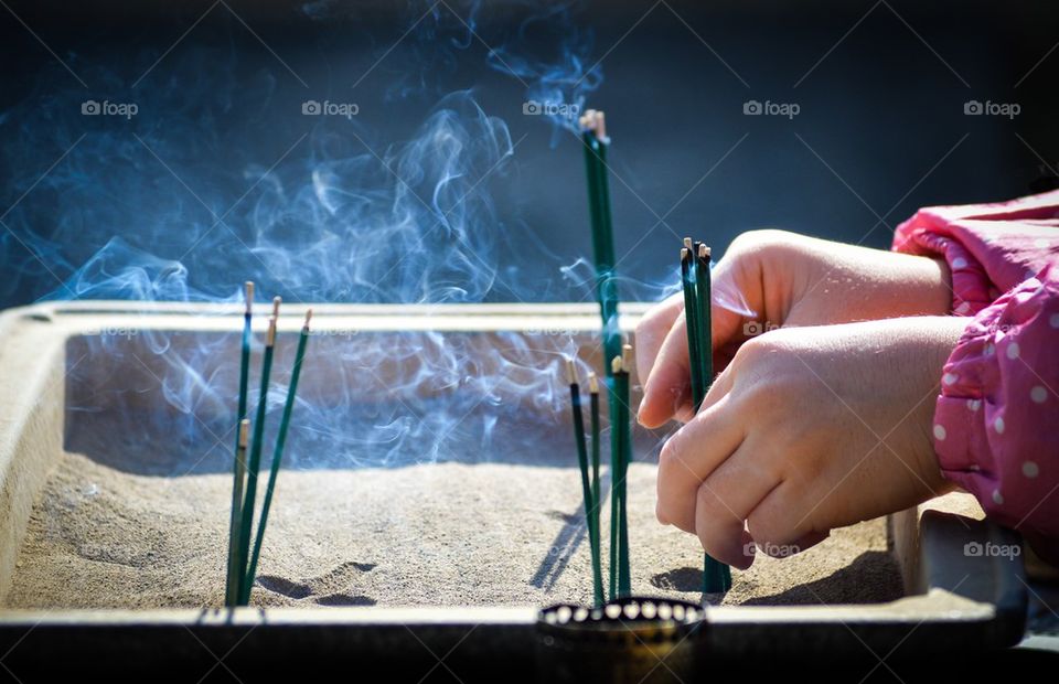 Child's hands placing incense.