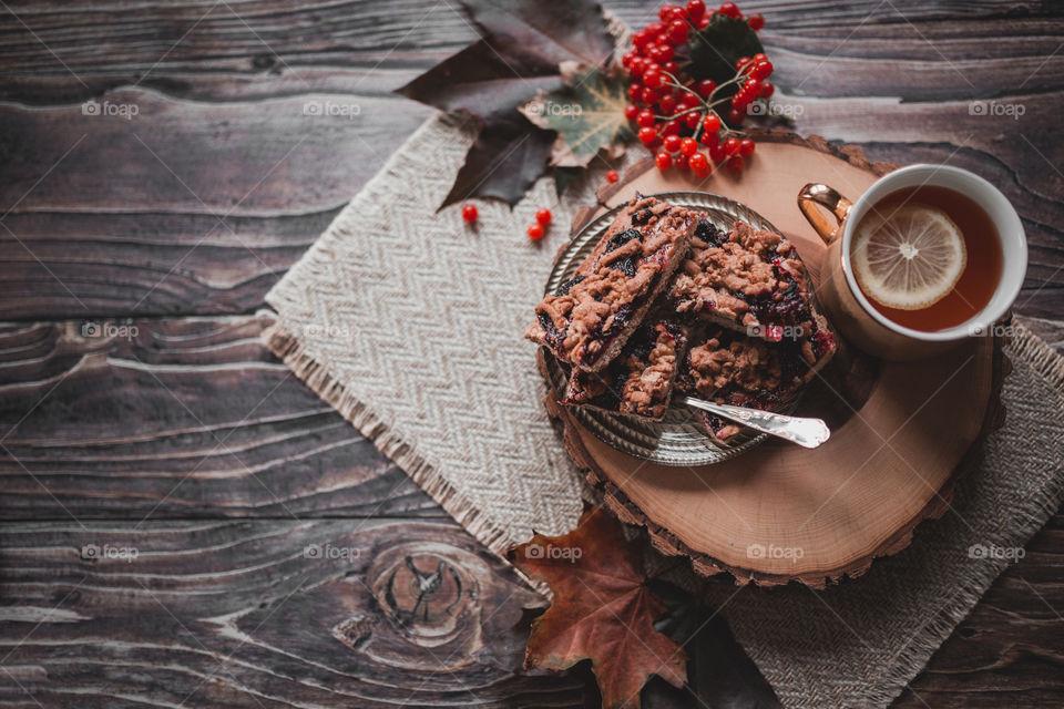 autumn pie with berries, a cup of hot tea on a wooden table with leaves