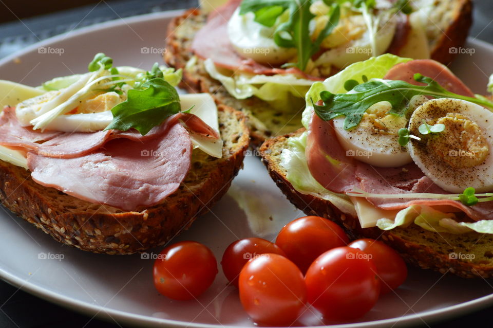 healthy breakfast full of vitamins - sandwitches of wholemeal bread with fresh lettuce, cheese, ham, egg, cress and cherry tomatoes