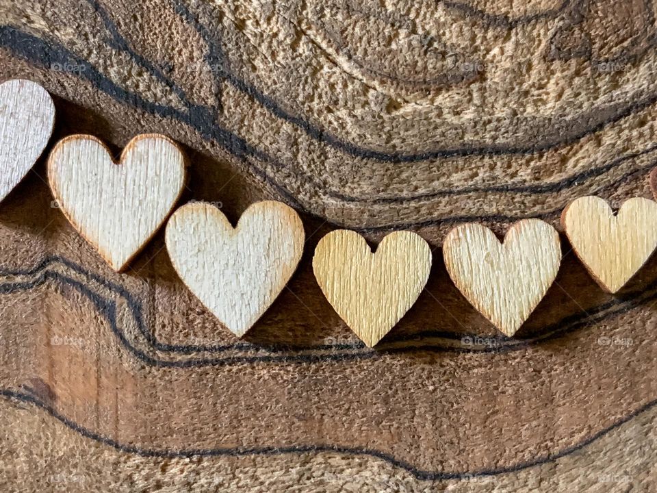 A row on wooden hearts against a wooden background 