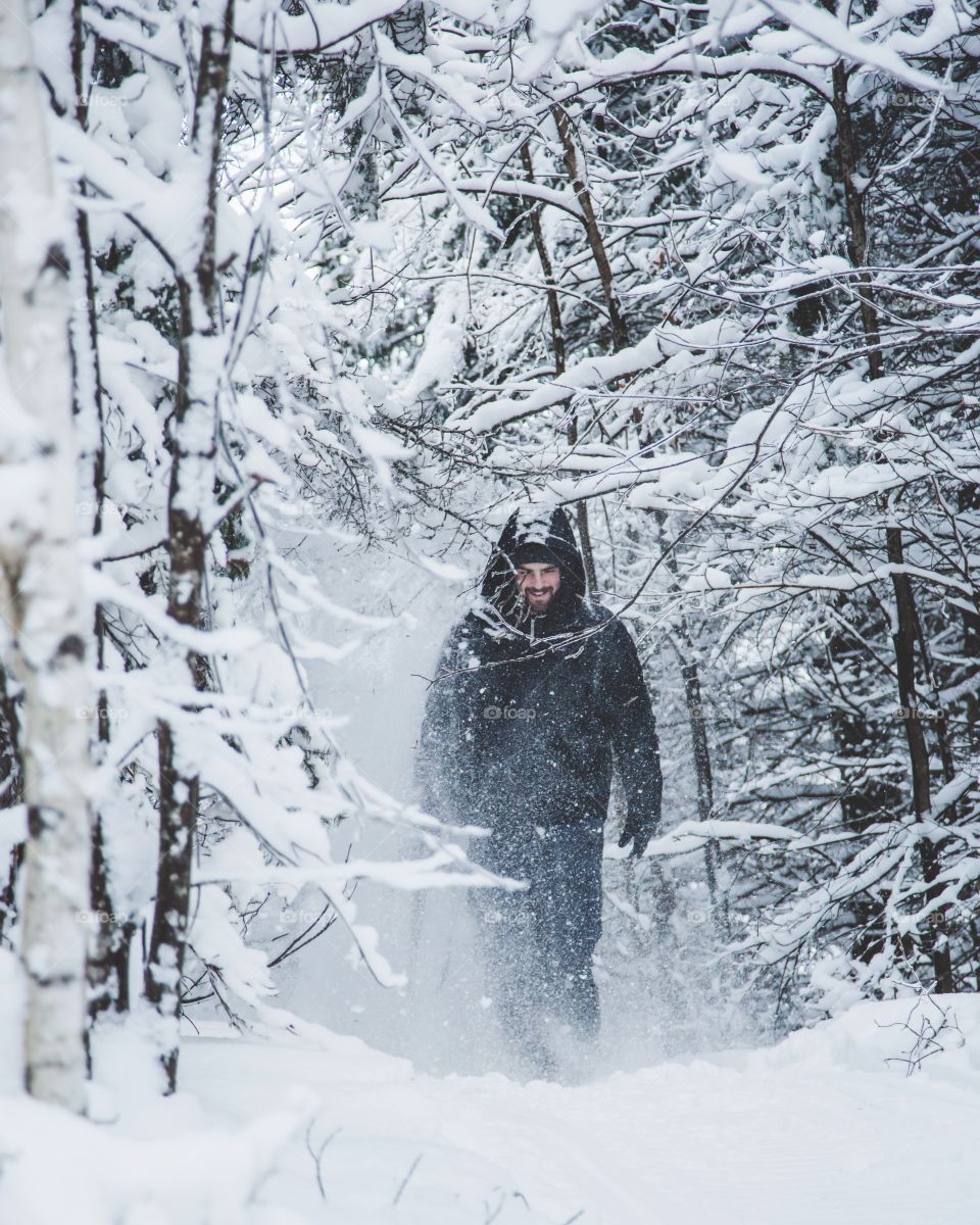 A young man walking through a snowy forest, exploring