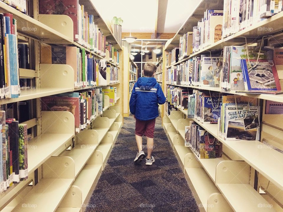 Boy walking down the stacks at the library 