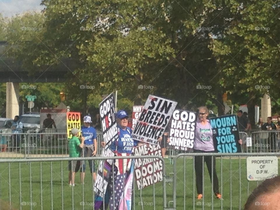 Westboro Baptist church members holding signs to protest an LGB club formed by students of IUPUI.  Club supporters and spectators stand in the background.