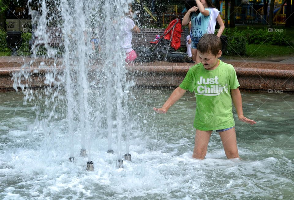 child in water fountain city summer time