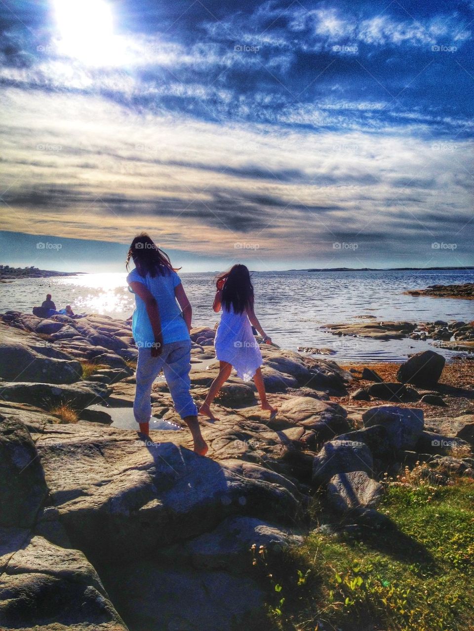 Girls running on the rocks towards the sea