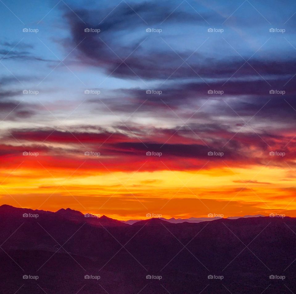 An incredible sunset behind a mountain range looks like fire in the sky one fall evening