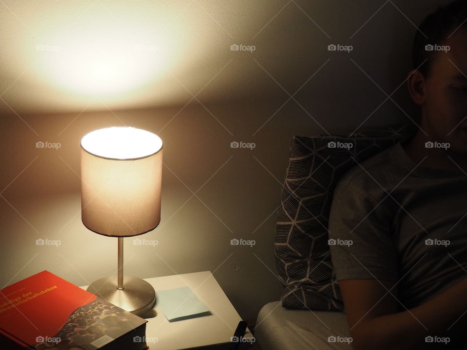 relaxed man is reading a book in bed at dimmed light