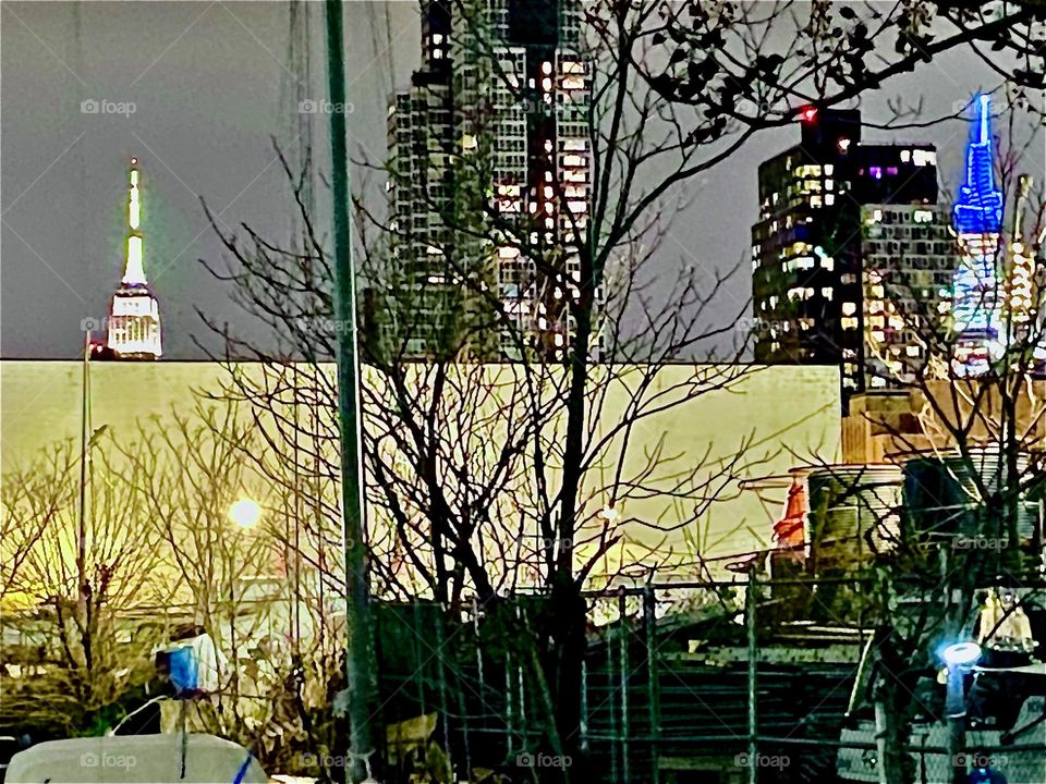 “Newtown Creek” at night w the “Empire State Building” in the background in “Manhattan”, NYC. Such impressive & fascinating views offer themselves frequently here where we live full time on our boat, the “Salvation”. 2022. Hypnotic Productions