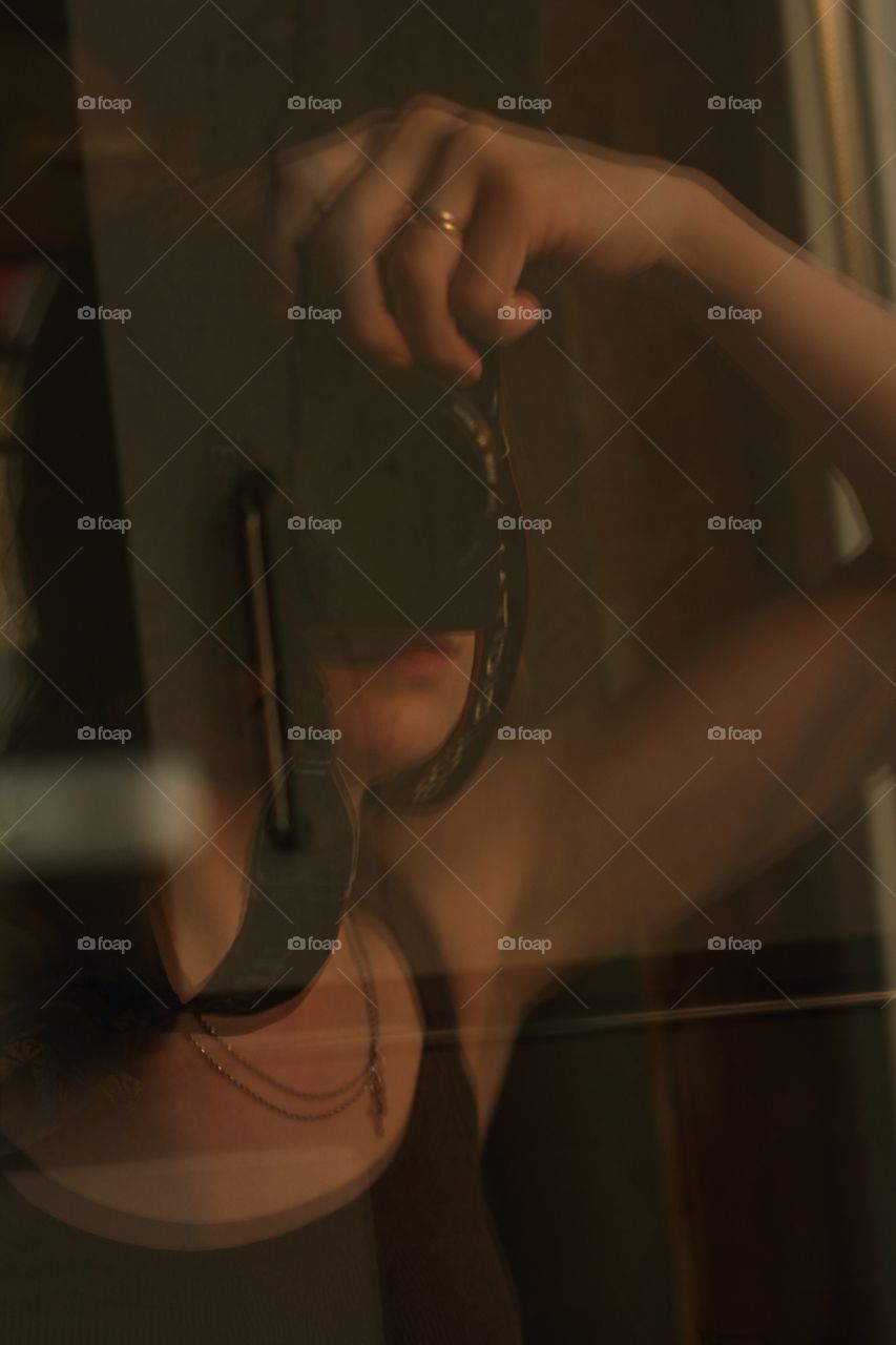 Girl makes selfie on a camera in the reflection of the kitchen window