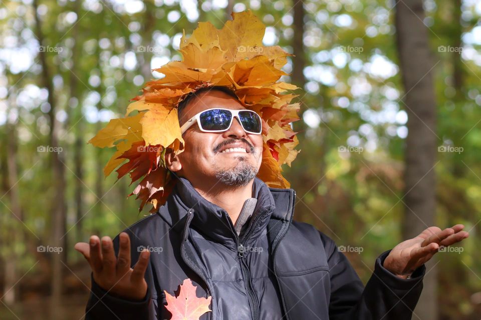 Hapy man in a crown of autumn leaves and a cool sunglasses