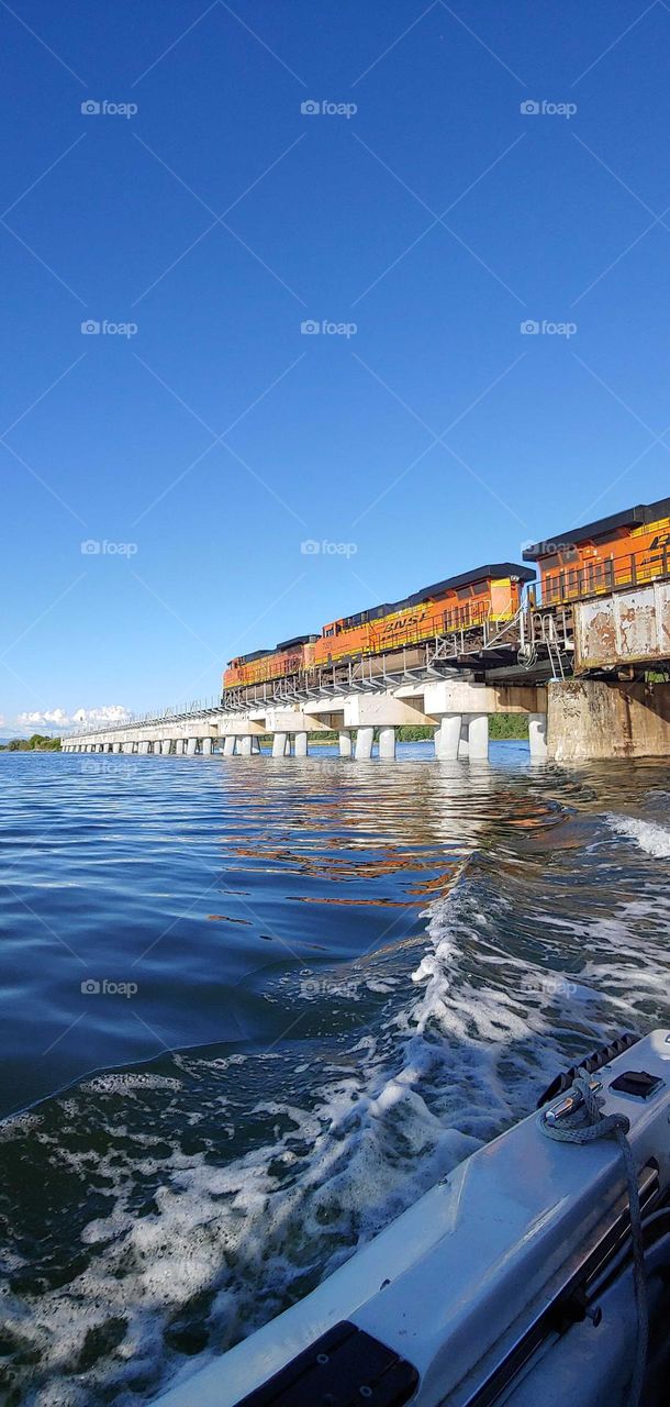 Cruising under the bridge as the train goes by .