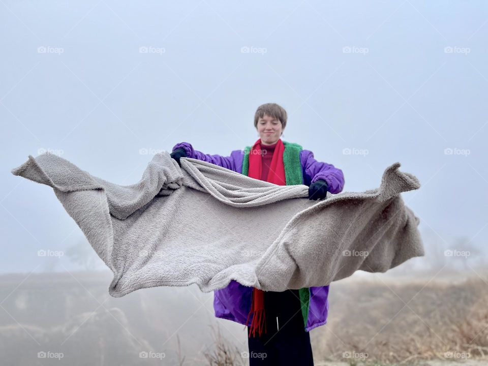 Cute happy girl playing with blanket on the top of the hill. 