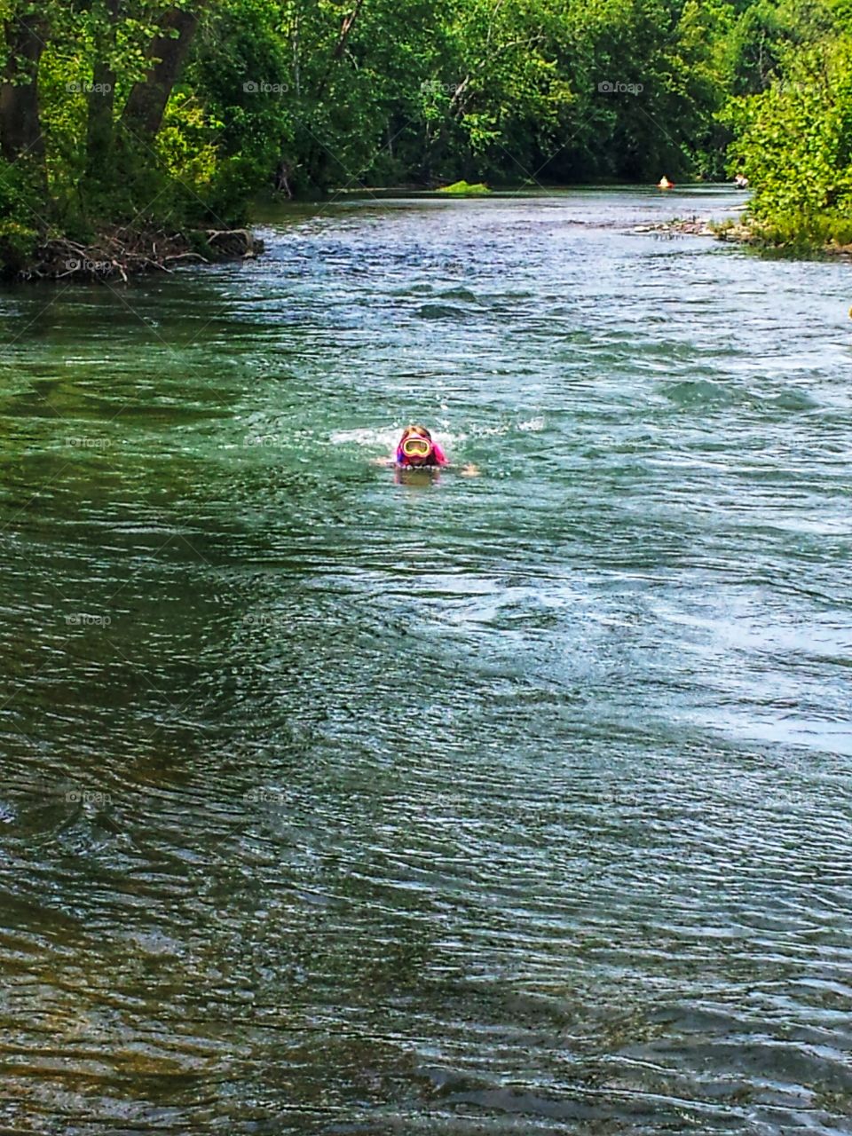 little girl swimming in a big river all by herself
