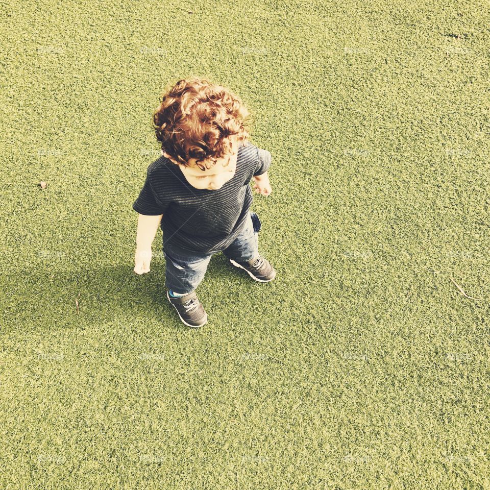Redhead little boy on grass. Top view