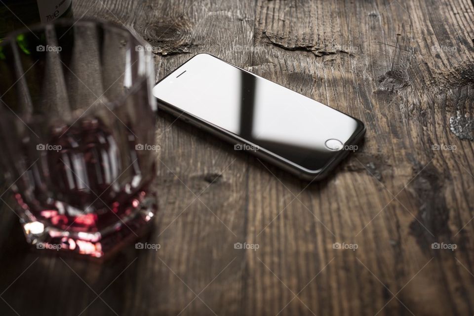 new iphone 6 on wooden table with glass of whiskey