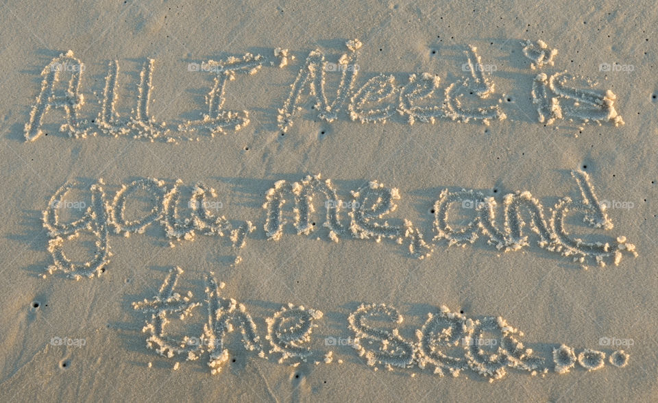 "All I need is you, me, and the sea..." written in sand at the beach