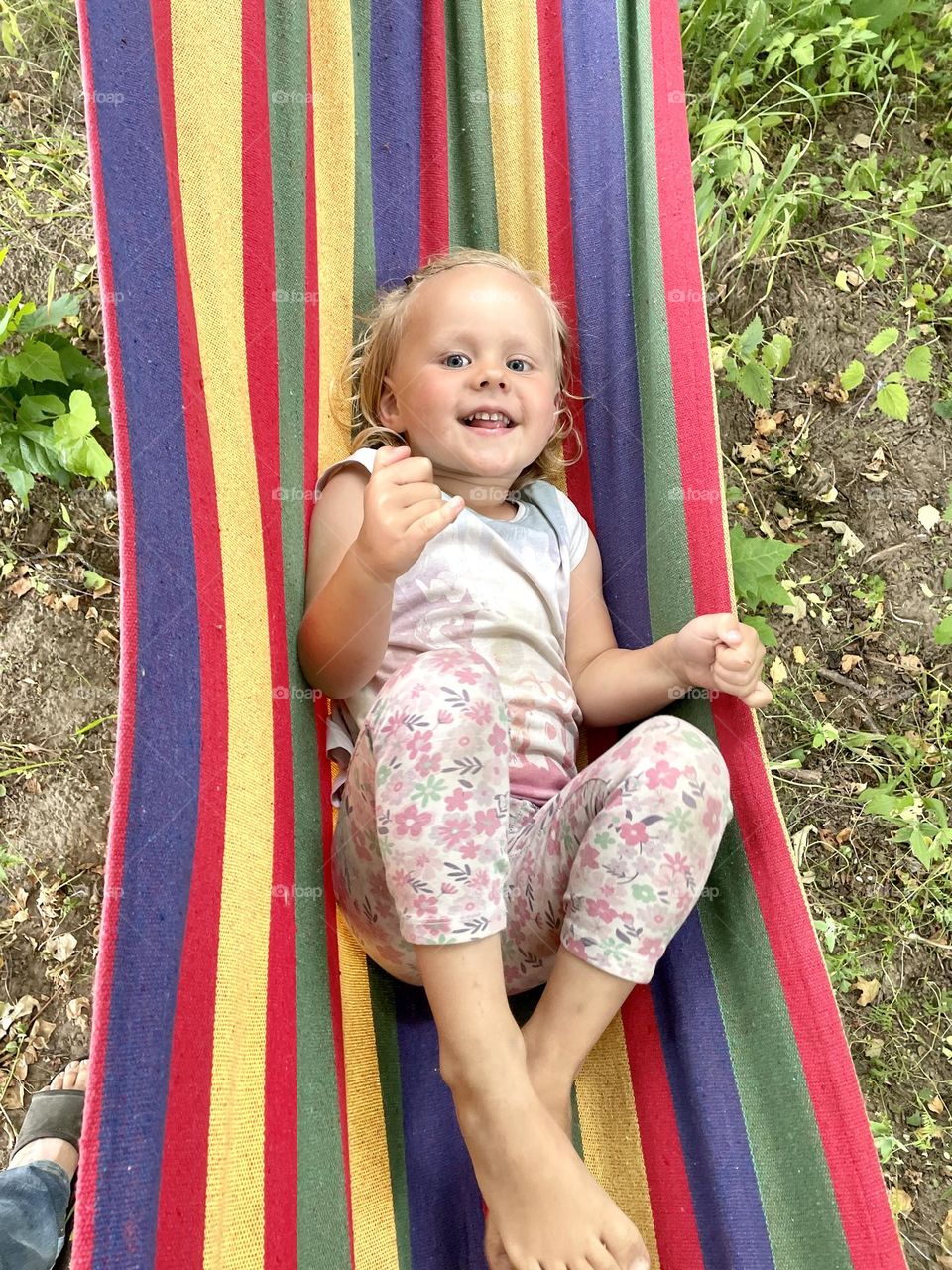 Baby girl in a hammock during sunny summer day.