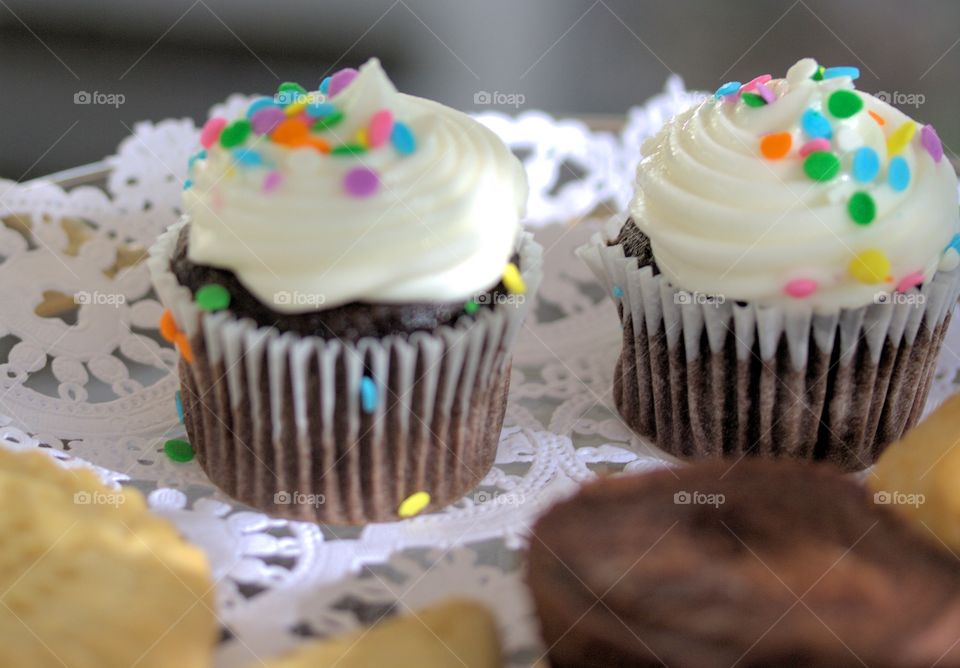 colorful confetti chocolate cupcakes with white vanilla frosting in a sunny setting