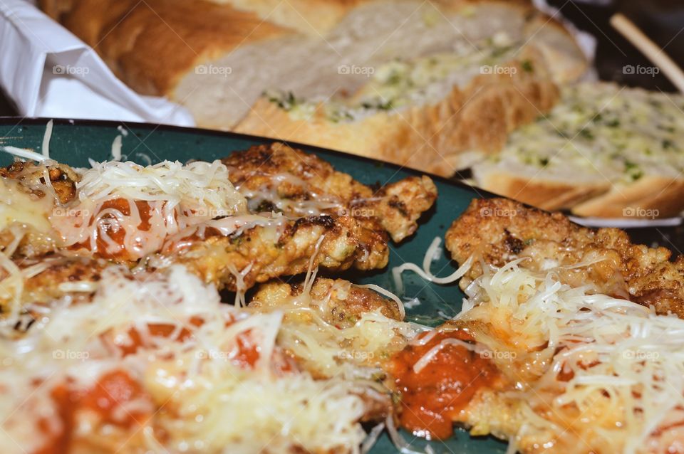 Chicken scaloppine Parmesan with fresh homemade garlic bread in background 